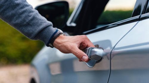 A close up view of an unrecognizable Caucasian male entering his vehicle. (cropped)